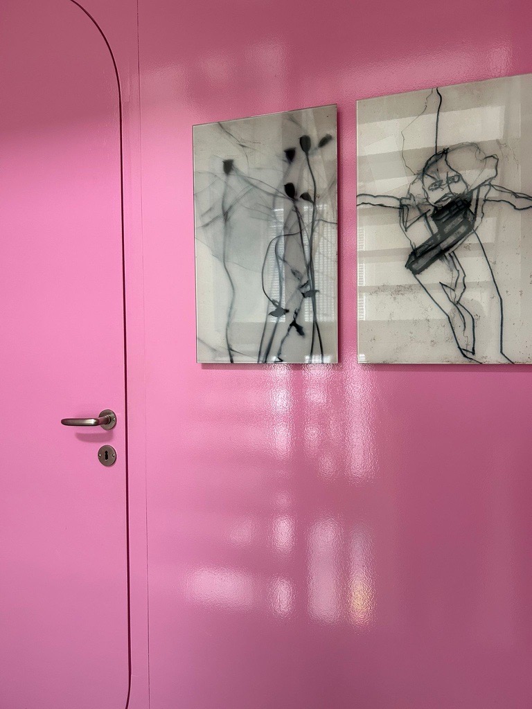 Kräftig pink gestrichene Wand- und Türfläche mit zwei gerahmten Arbeiten